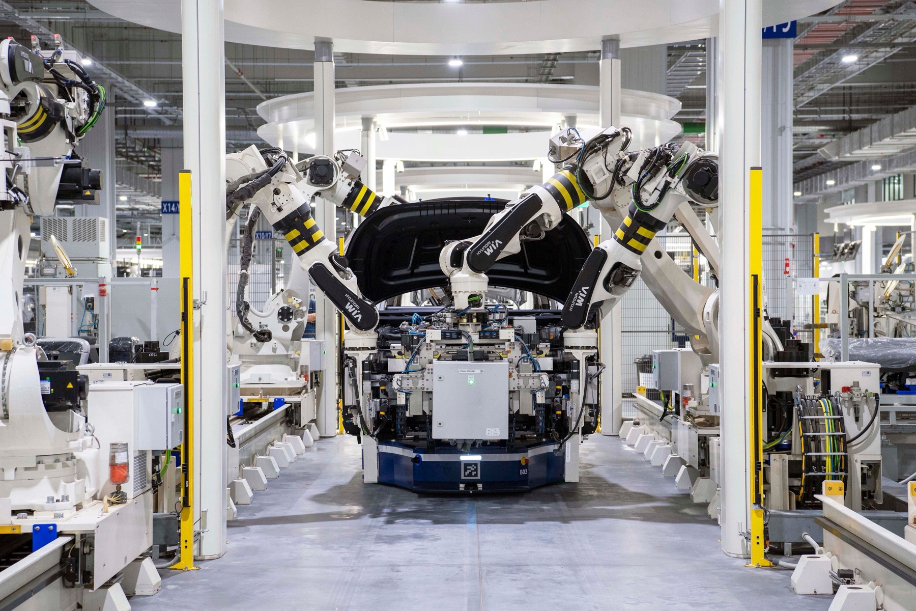 Robotic arms assembling a vehicle in an automotive manufacturing plant